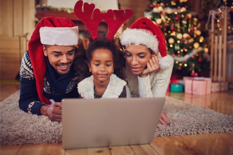 Family wearing christmas hats watching something on a laptop